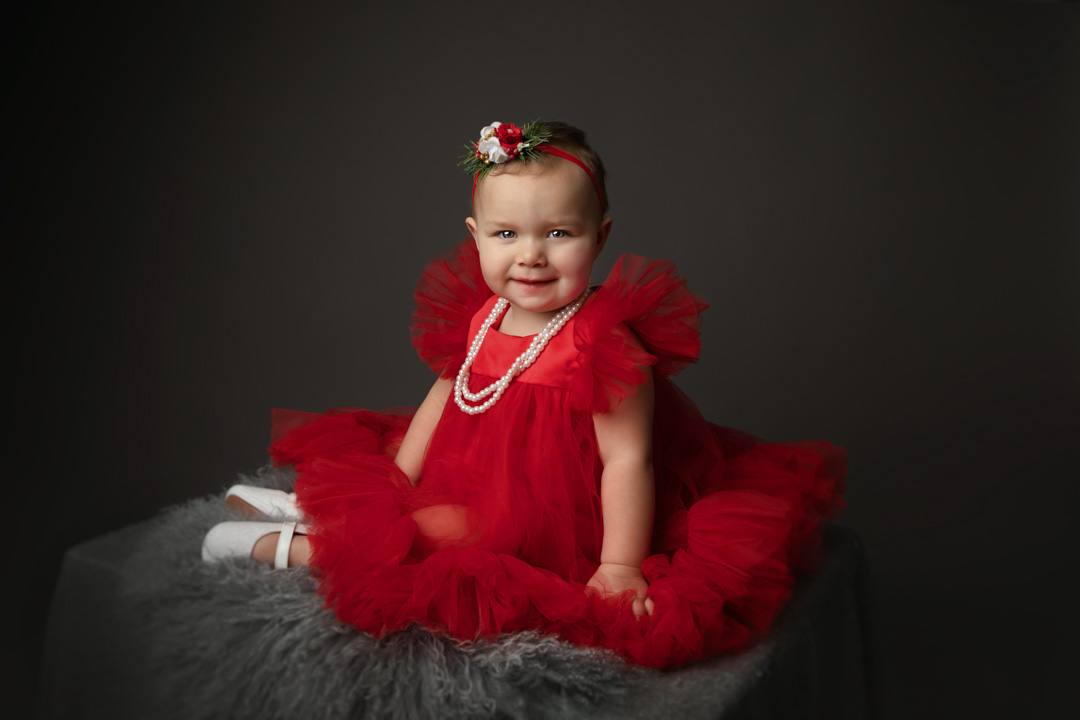 Baby girl in a red dress during a milestone photography session in Ana Koska's Timonium studio