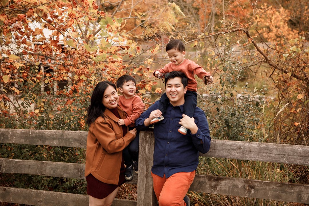 Parents and their two young children smiling together during an autumn family session