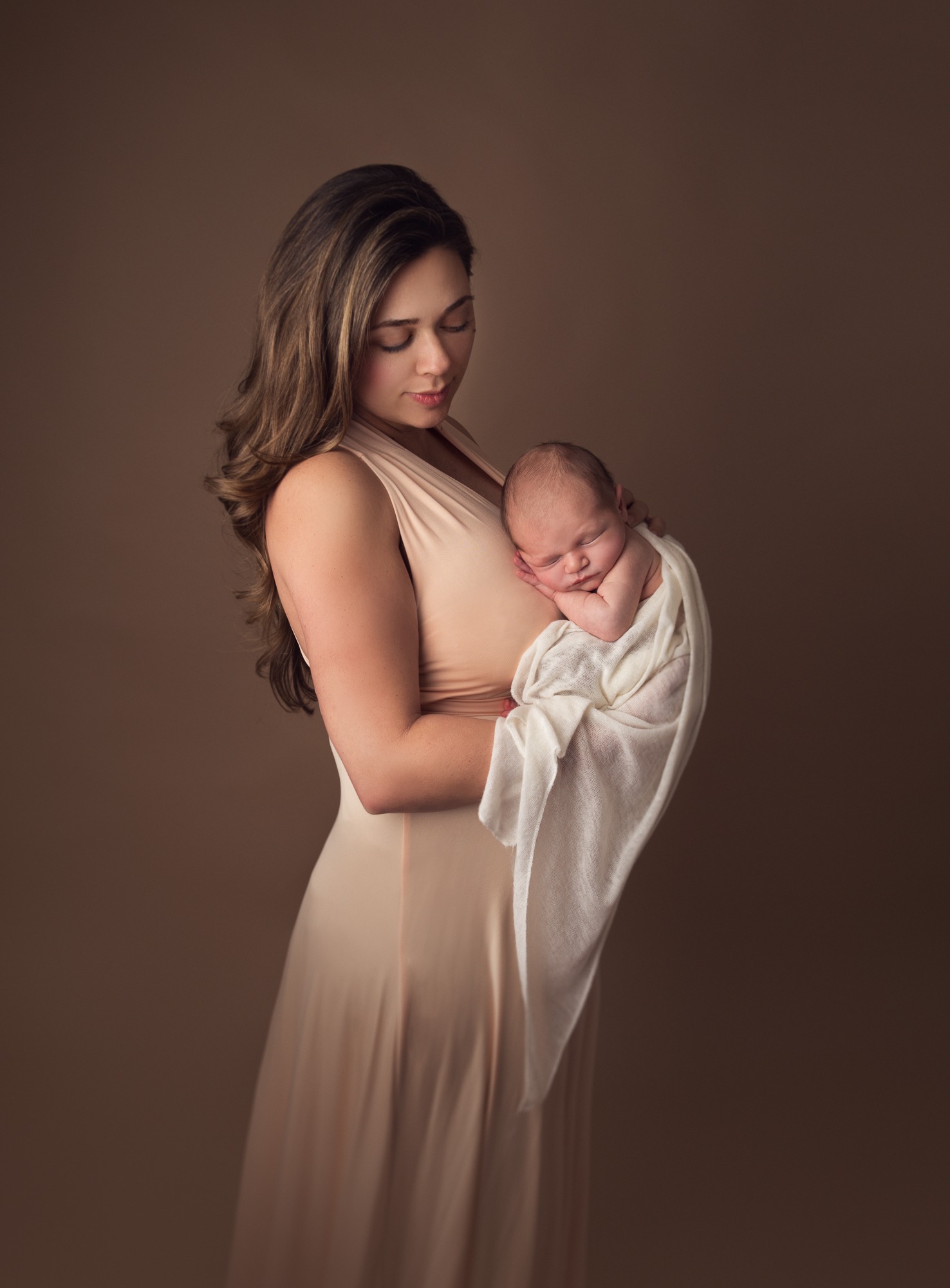 Mother holding her newborn during a warm studio portrait session