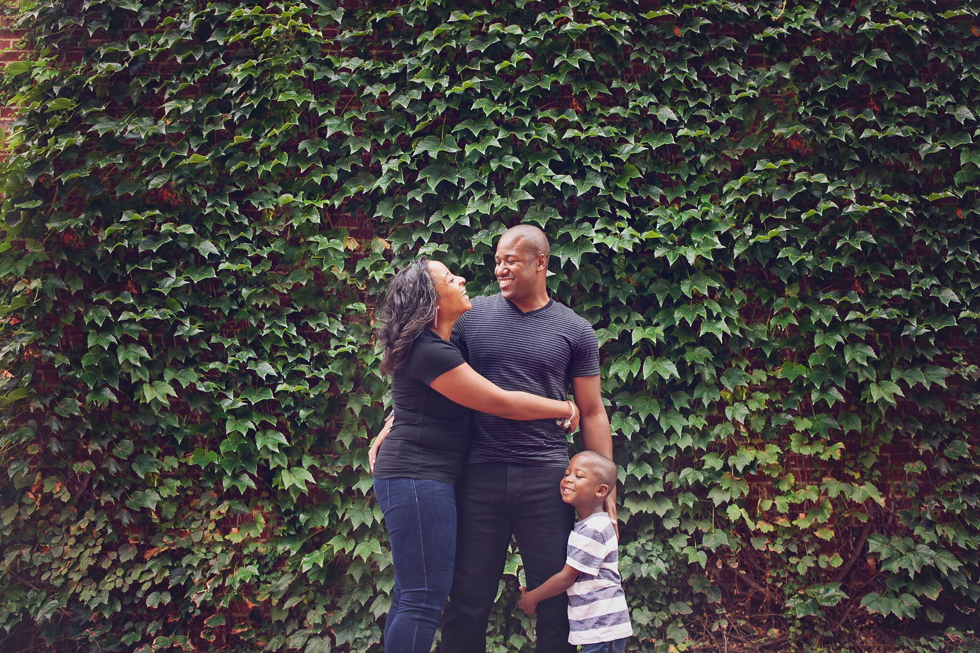Family of three in front of leaf wall