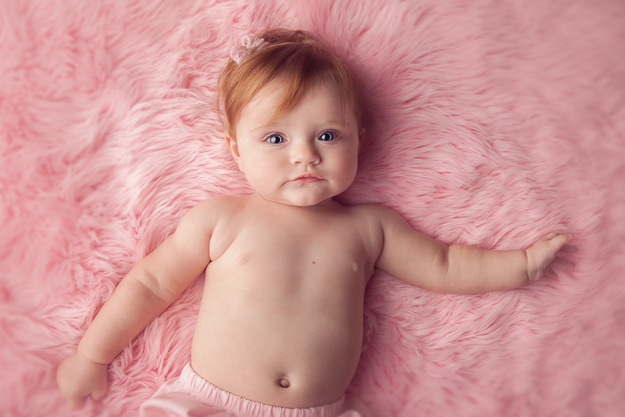 Baby girl photographed on a soft pink studio setup