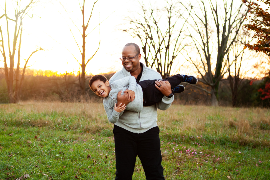 Father playing with his young son during a golden-hour fall family photography session