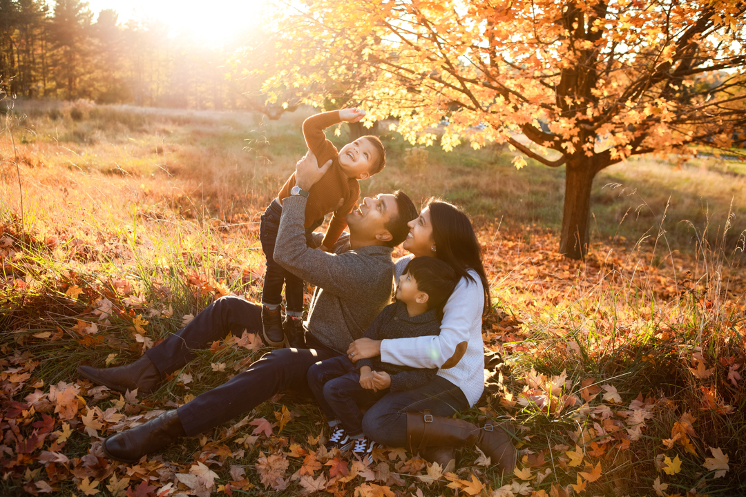 Family of four together beneath glowing autumn trees during a Baltimore-area portrait session