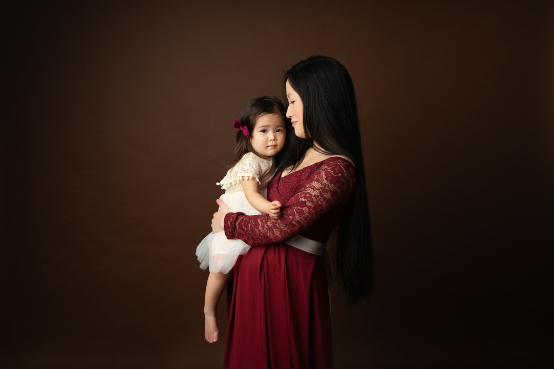 Expectant mother holding her young child during a studio maternity session in Timonium, Maryland