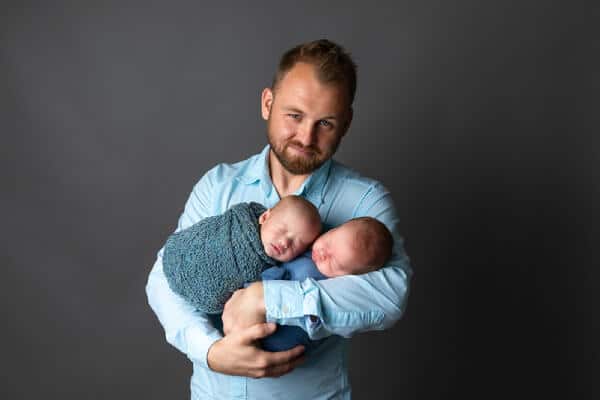 Dad holding twin newborn in blue swaddle - Baltimore studio portrait