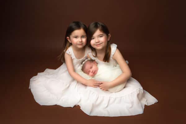 Sisters holding newborn in photo session