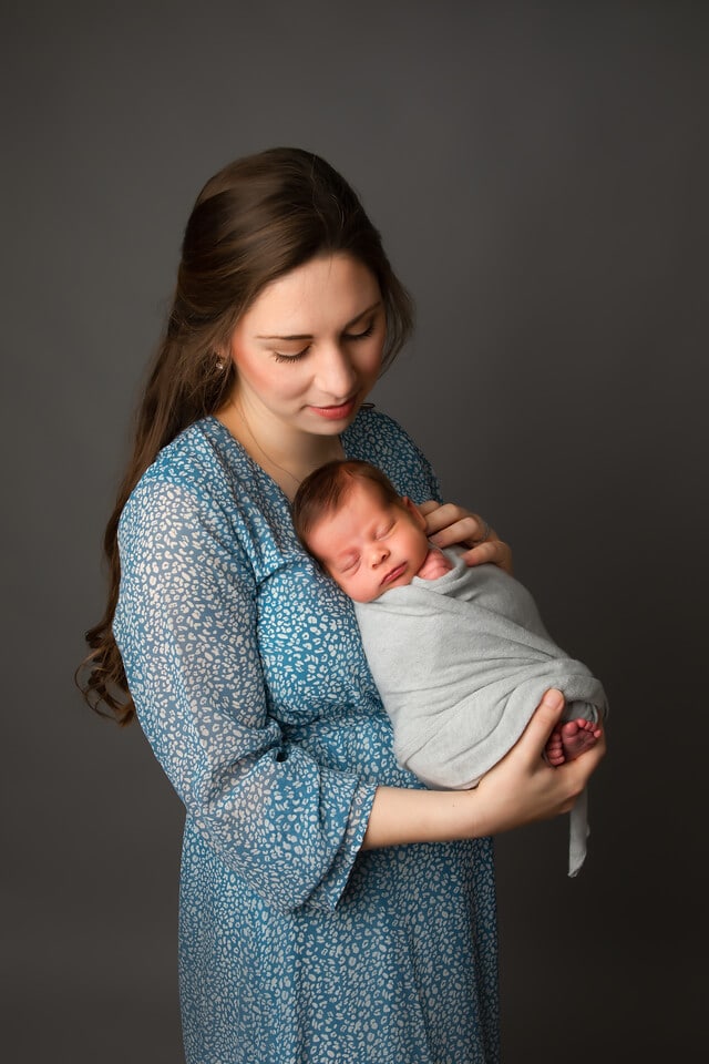Mother holding sleeping newborn baby during a posed newborn photography session in Baltimore Maryland
