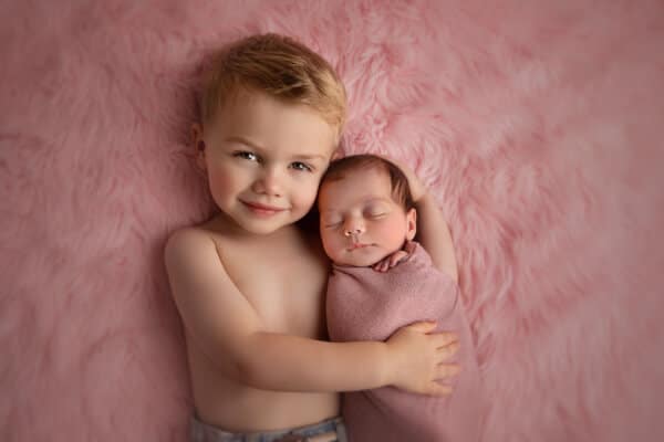 Toddler hugging newborn in Baltimore studio