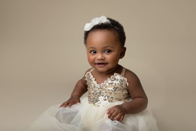 Baby girl in white dress smiling during a session