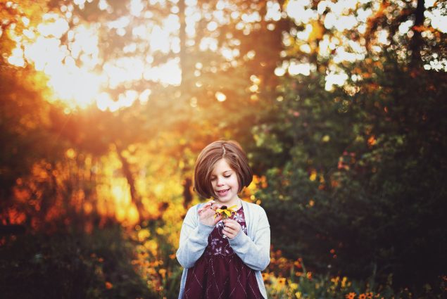 Girl holding a yellow flower in outdoor session