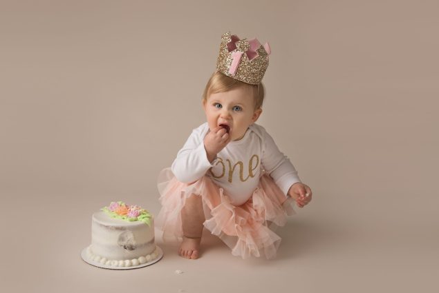 Milestone session with a baby girl eating a cake