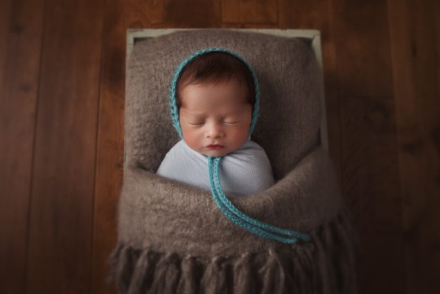 Newborn sleeping in a crate