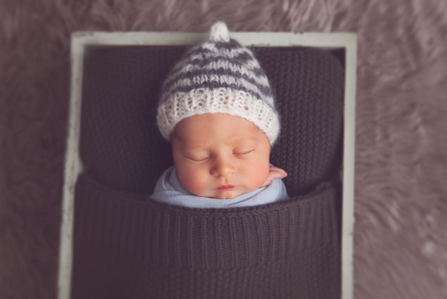 Newborn sleeping in prop crate