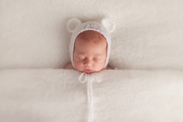 Newborn sleeping under white blanket