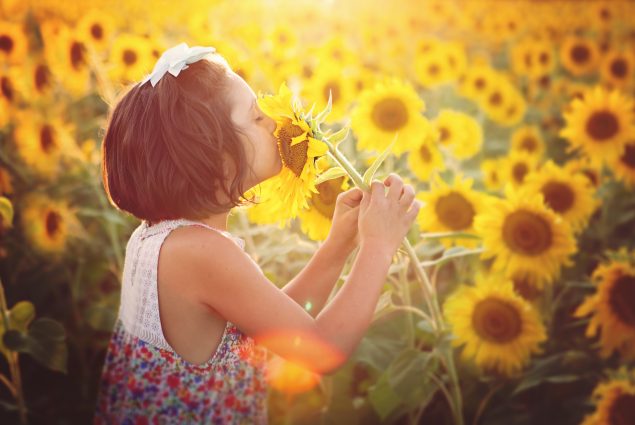 Picture of a girl smelling a sunflower in an outdoor session
