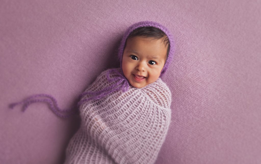 Newborn girl in purple swaddle setup