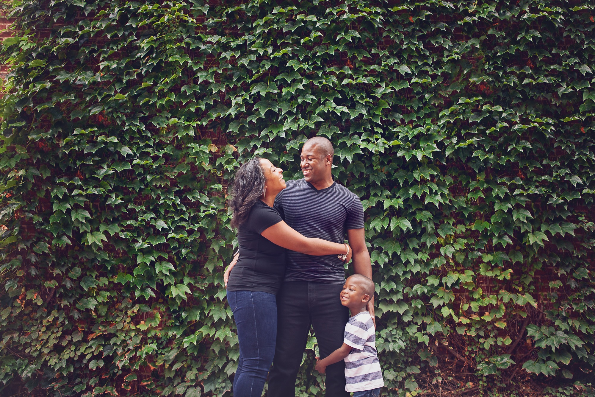 Family of three in front of leaf wall