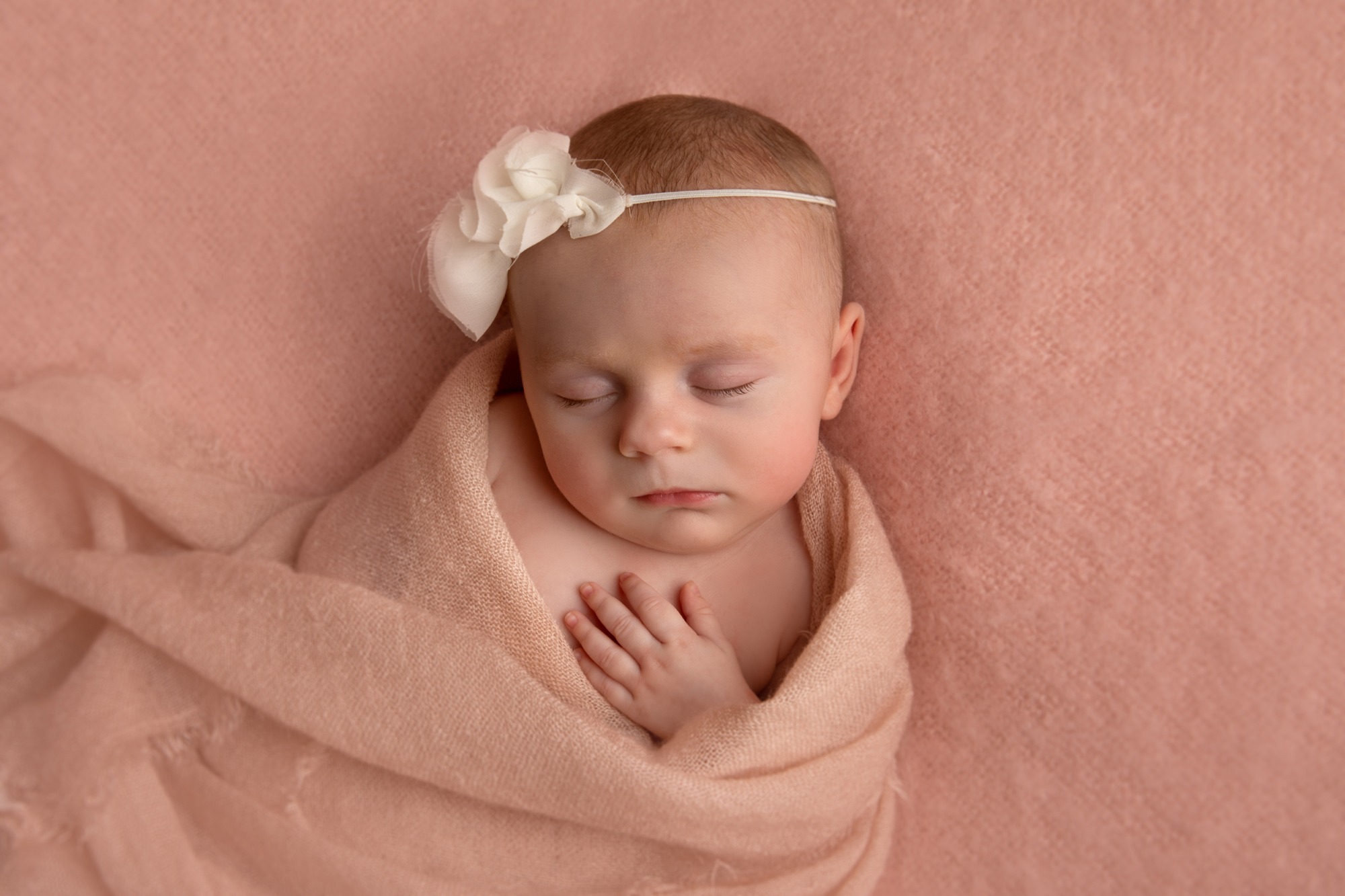 Newborn with white headband in studio photoshoot