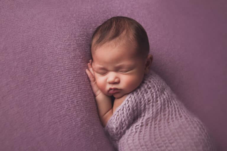 Newborn photo session in a Baltimore studio with a sleeping wrapped baby