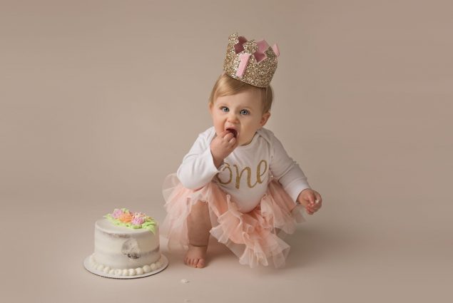 Milestone session with a baby girl eating a cake