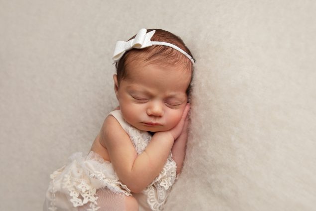 Newborn baby girl sleeping on white blanket