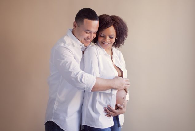 A couple in white shirts in studio maternity photography session