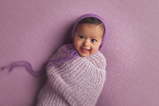 Newborn girl in purple swaddle setup