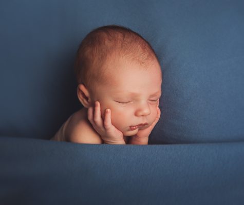 Newborn sleeping under blue blanket