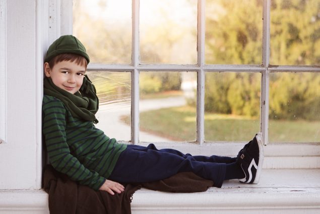 Professional portrait of boy sitting in the window