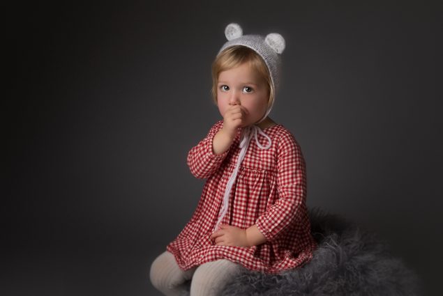 Studio portrait of a toddler girl sucking her thumb